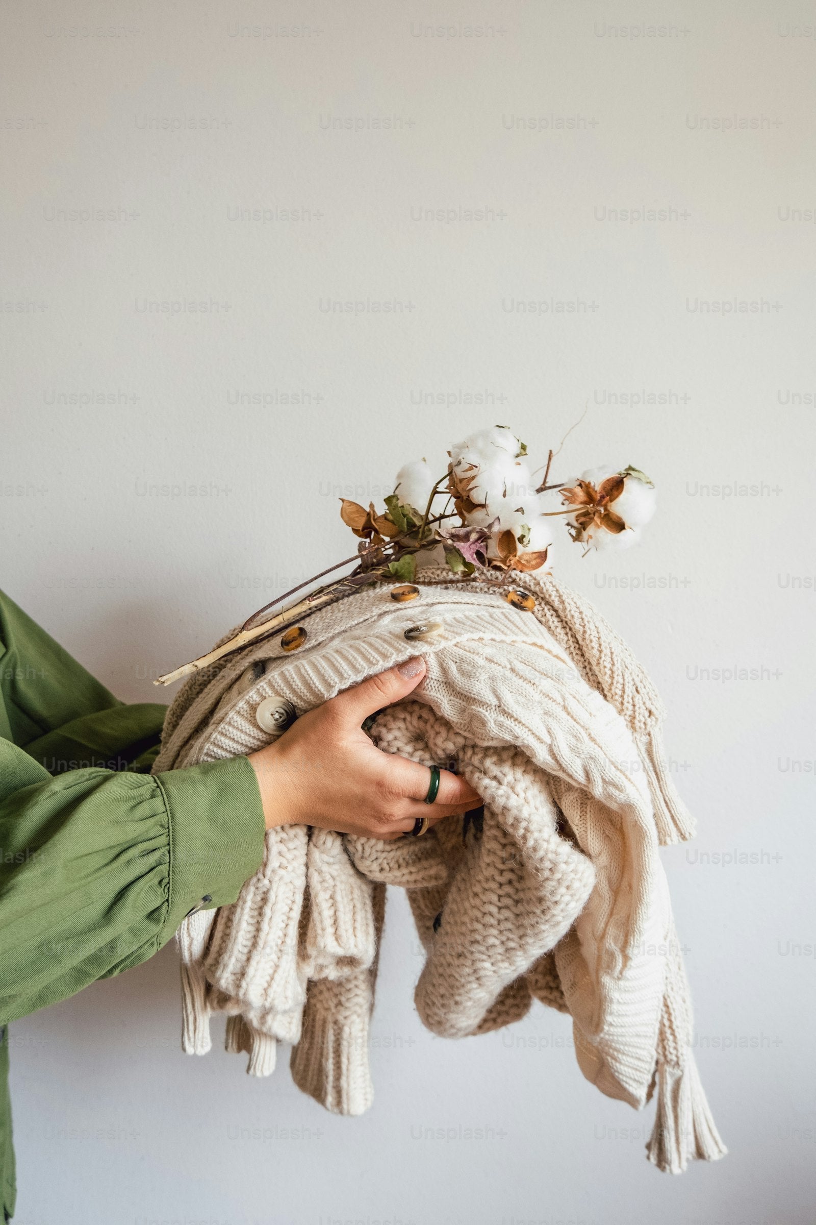 Personne tenant une pile de chandails en laine et des fleurs