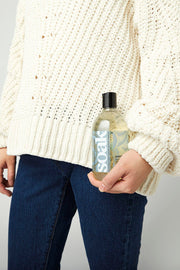 Flacon de lessive Soak Scentless 375 ml posé près d'un pull tricoté beige, ambiance entretien