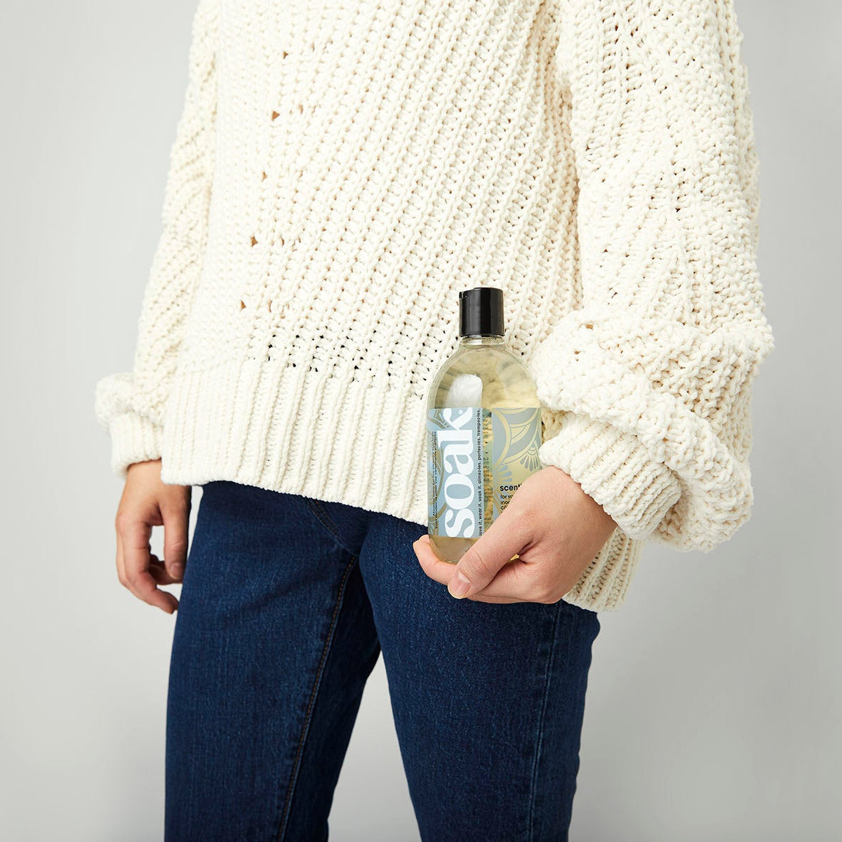 Flacon de lessive Soak Scentless 375 ml posé près d'un pull tricoté beige, ambiance entretien
