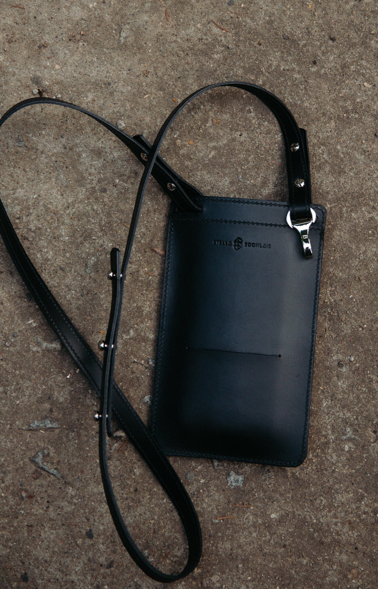 Dos de la pochette téléphone en cuir noir Stella Soomlais avec mousqueton nickel et logo embossé