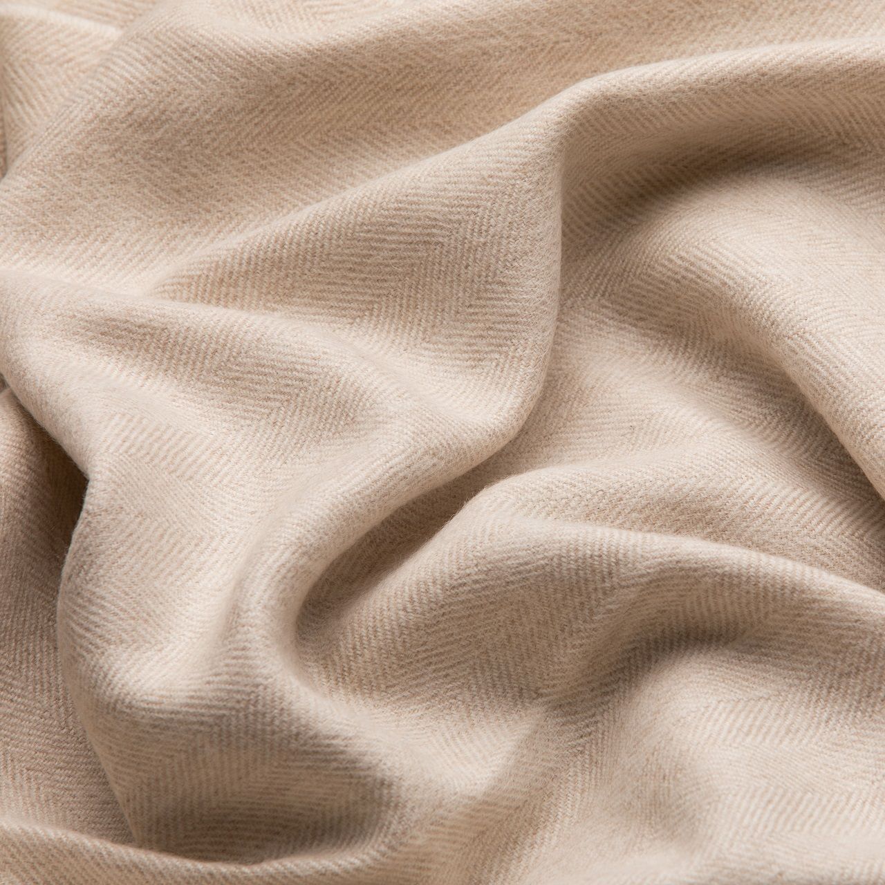 Détail rapproché d'une écharpe en alpaga motif chevrons blanc et beige, texture visible