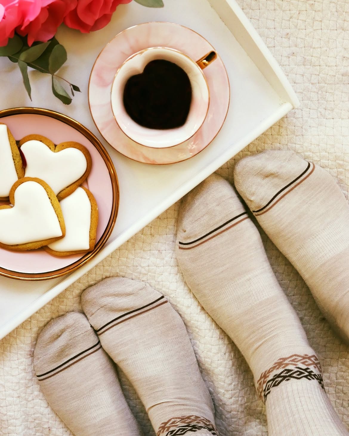 Chaussettes en laine mérinos claires à rayures portées près d'un plateau de café et de biscuits, Baltland