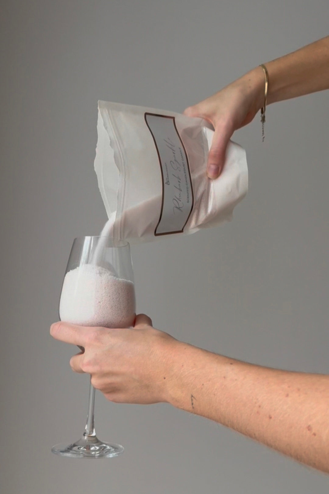 Versement de poudre Candledust dans un verre transparent, geste de remplissage