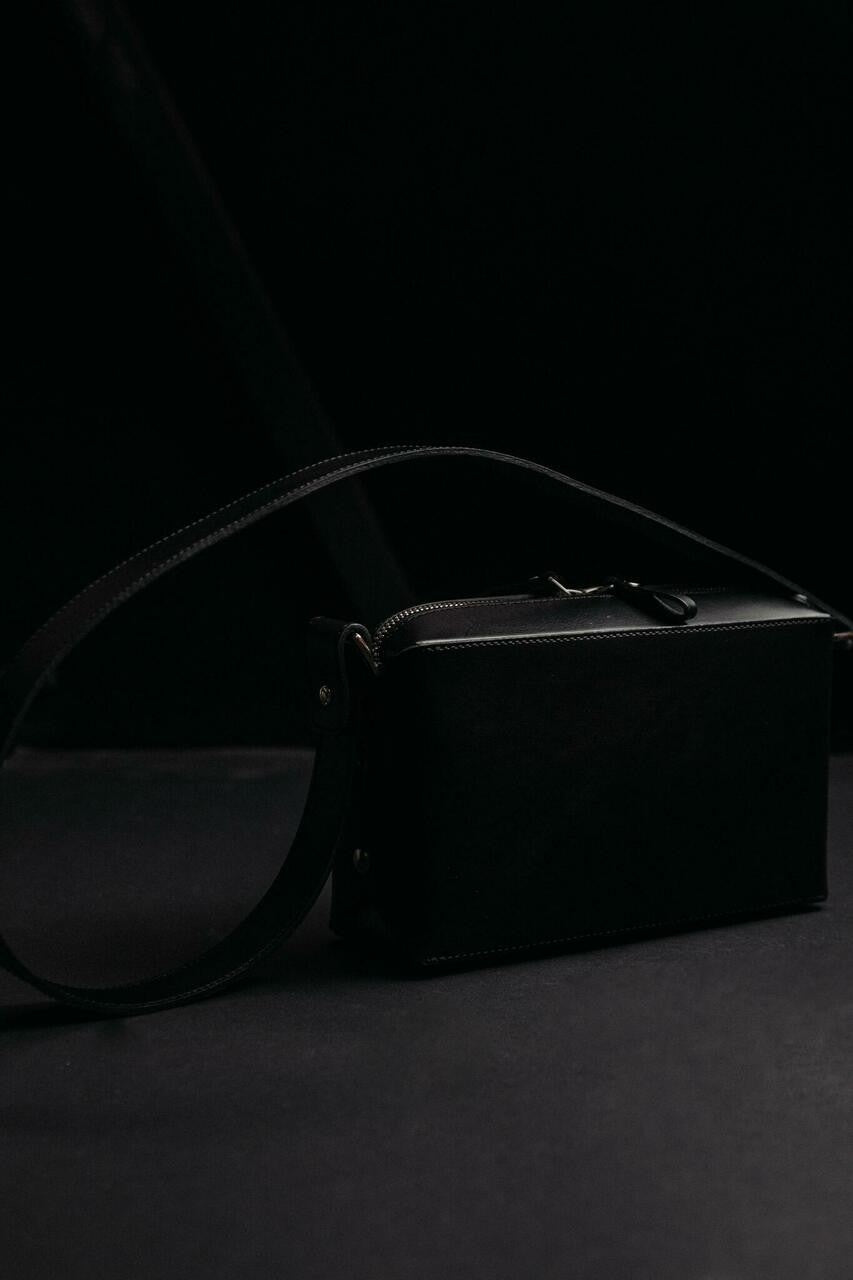 Sac bandoulière en cuir noir Stella Soomlais, vue de profil sur fond noir