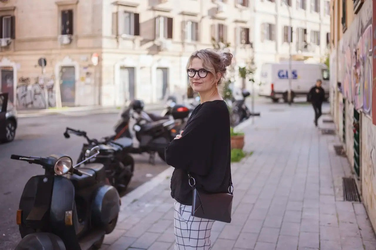 Sac à main en cuir noir Stella Soomlais porté en travers du buste, scène de rue