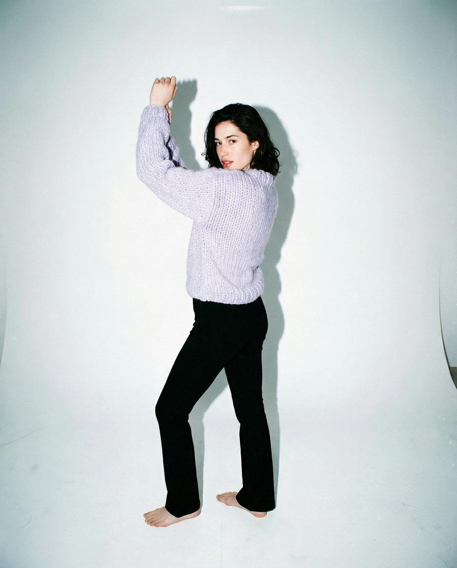 Pull en grosse maille de laine lilas tricoté main LeGarage Knitwear, bras levés sur fond blanc