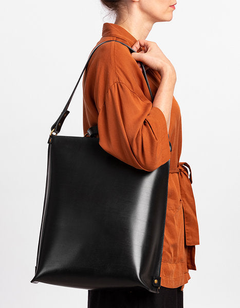 Sac à dos en cuir noir Stella Soomlais, porté à l'épaule en version sac à main