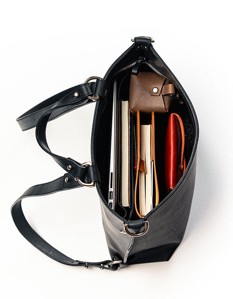 Sac à dos en cuir noir Stella Soomlais, vue de dessus ouvert avec ordinateur et carnets