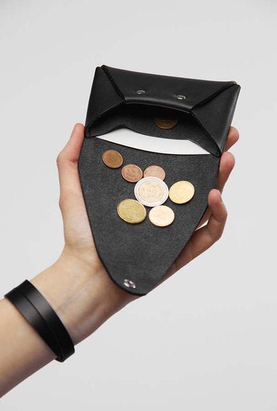 Porte-monnaie en cuir noir Stella Soomlais déplié dans la main avec pièces en euros