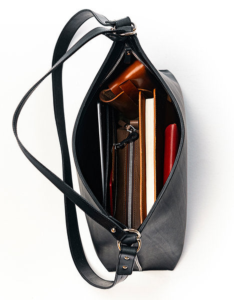 Sac à main en cuir noir Nothing to Declare Stella Soomlais, intérieur ouvert avec carnets et trousse