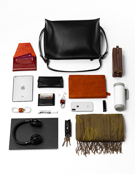 Sac à main en cuir noir Nothing to Declare Stella Soomlais, entouré de tout ce qu'il peut contenir