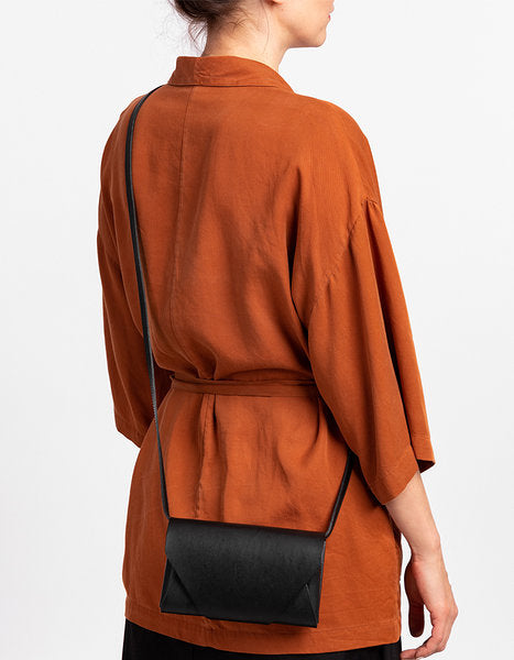 Pochette-portefeuille en cuir noir Stella Soomlais portée en bandoulière, vue de dos du mannequin