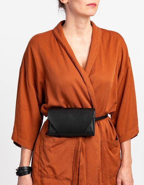 Pochette-portefeuille en cuir noir Stella Soomlais portée à la taille sur ceinture, façon sac banane