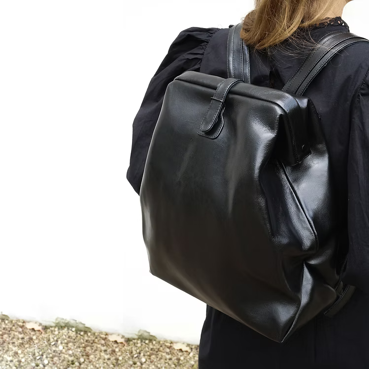 Sac à dos en cuir noir brillant RR, porté à l'épaule, détail texture