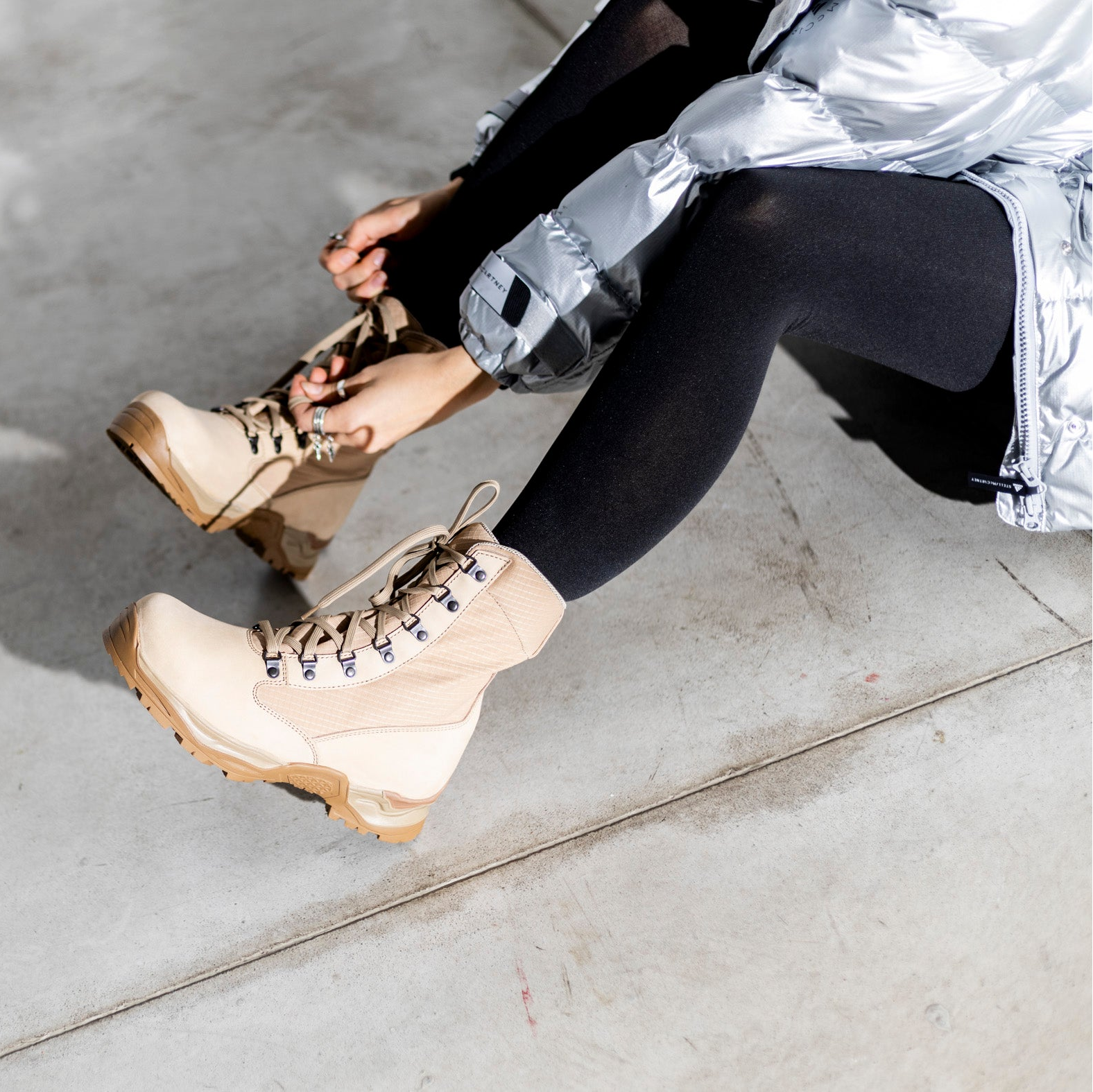 Bottines OmaKing en cuir naturel beige portées en lifestyle avec doudoune argentée et collants noirs sur sol béton