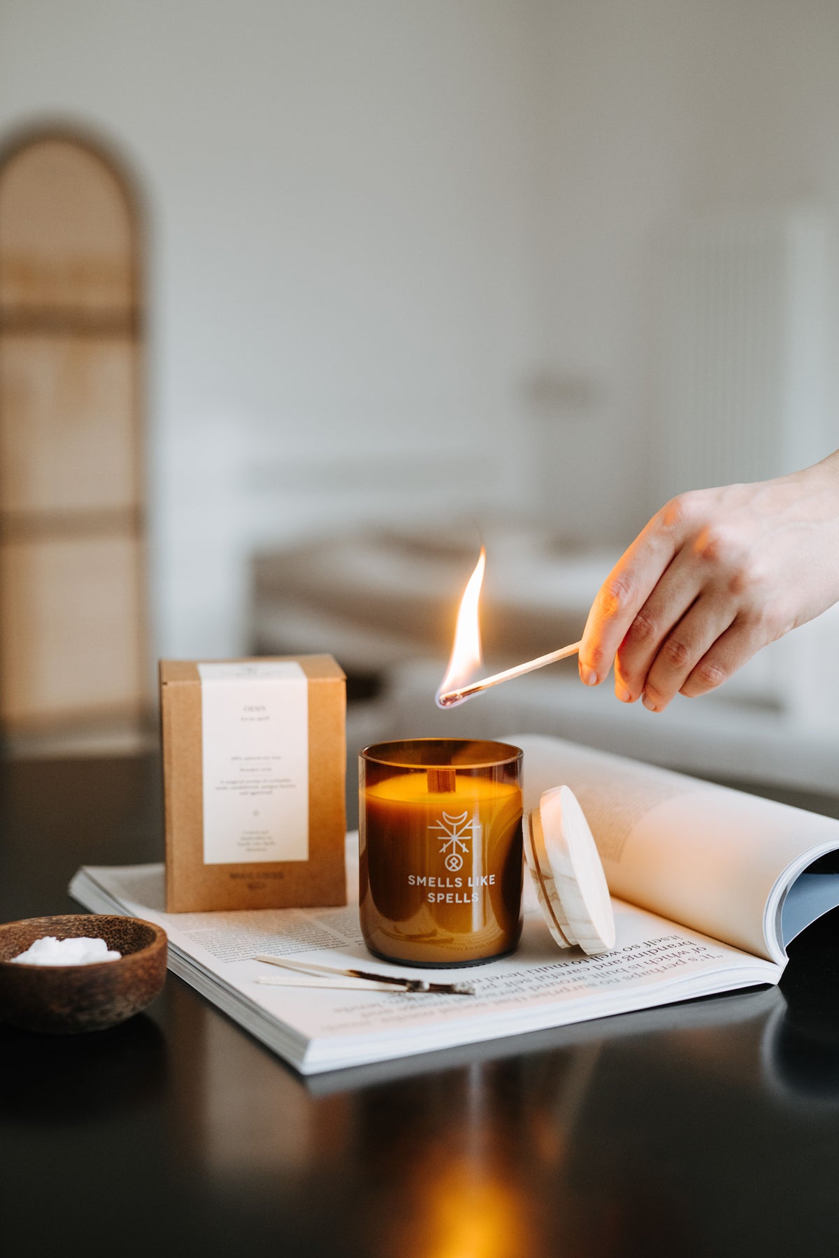 Bougie parfumée Smells Like Spells en verre ambré allumée à la main, vue lifestyle