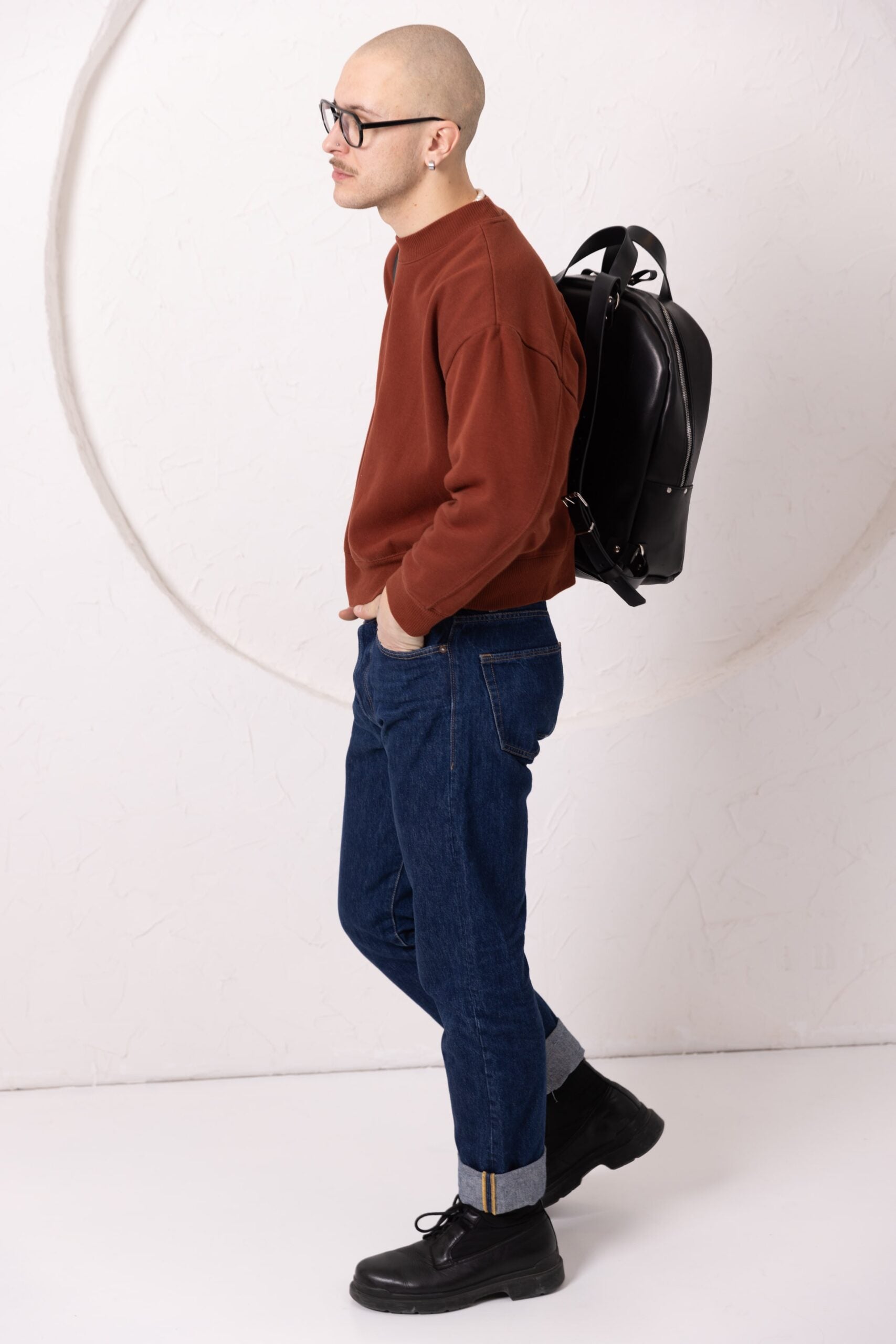 Sac à dos en cuir noir, détail du fermoir et des sangles, vue trois quarts