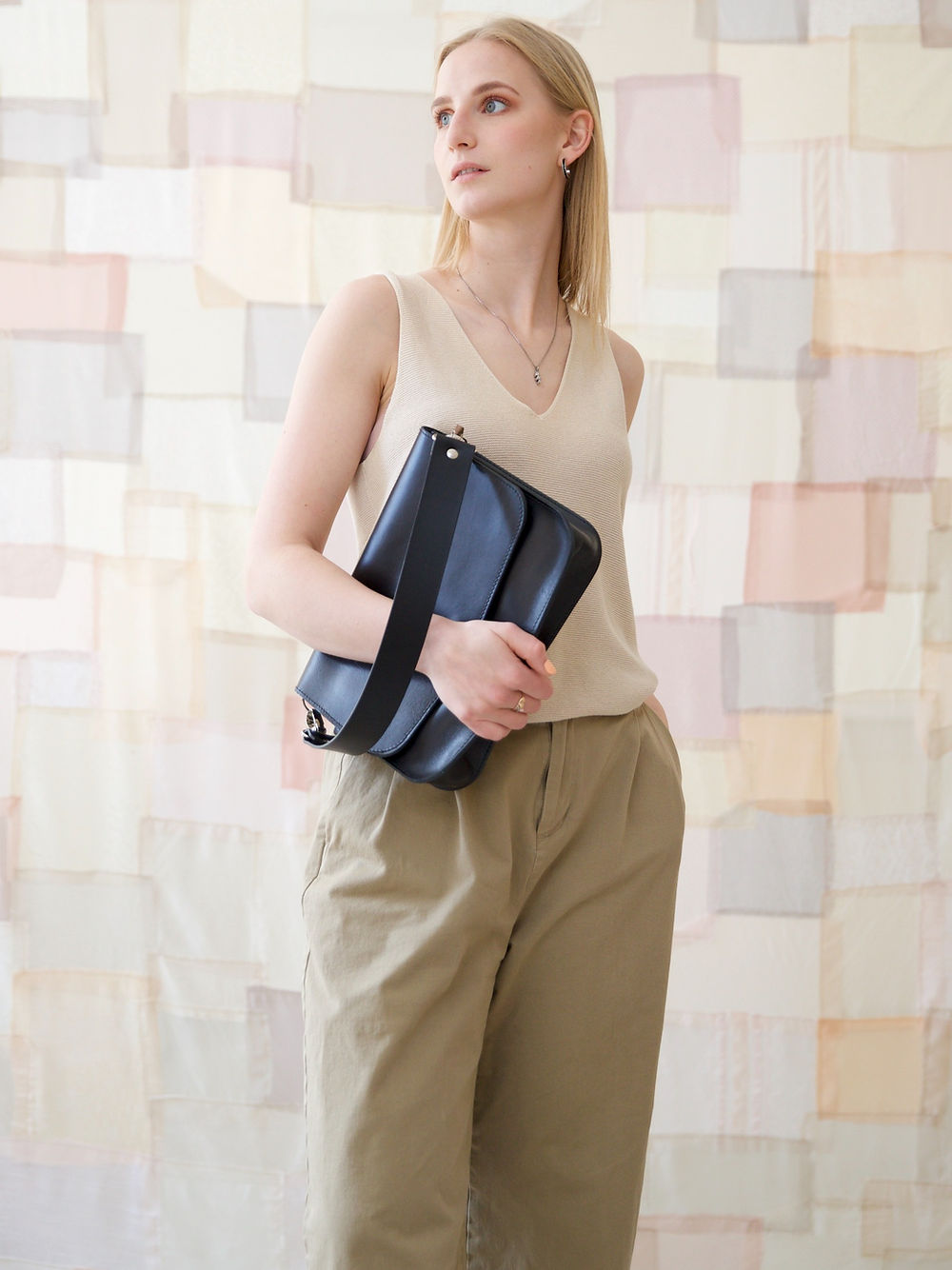 Sac à main ASTORIA TOKS VISOKS en cuir noir, porté sous le bras avec tenue tricot écru et pantalon kaki