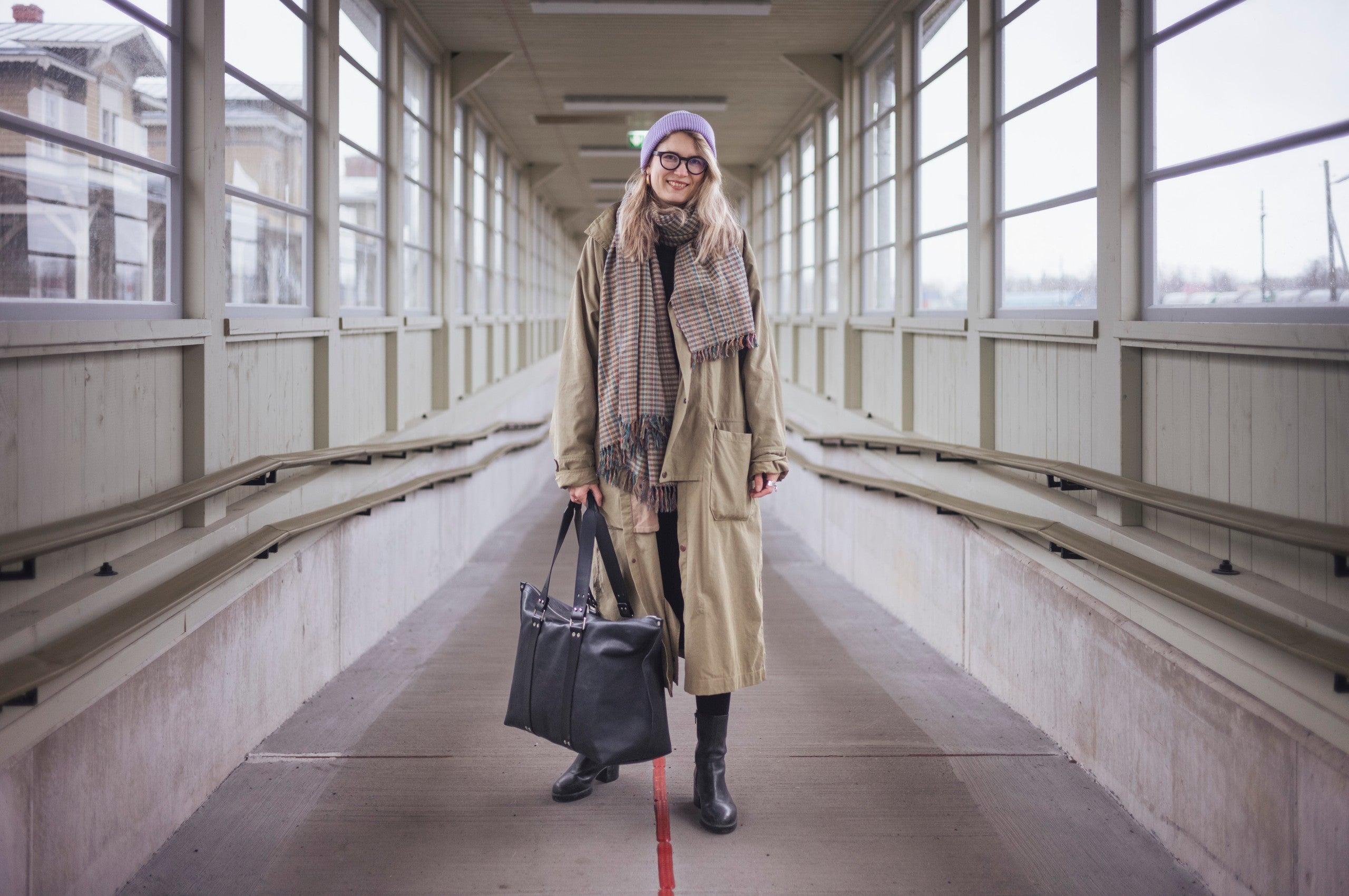 Sac week-end en cuir noir Stella Soomlais, tenu à la main dans une passerelle couverte
