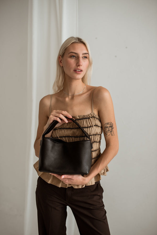 Sac Lava flow MERU porté épaule en cuir tanné végétal italien, sur top beige plissié, atelier de Marijampole