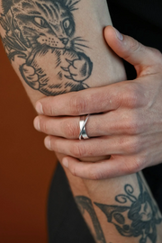 Bague Andromeda NO MORE en argent sterling portée sur un bras tatoué motif chat