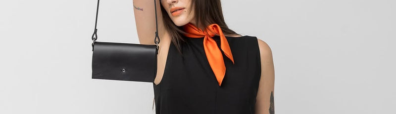 Femme en robe noire tenant petit sac en cuir PYKOK Kora par une anse