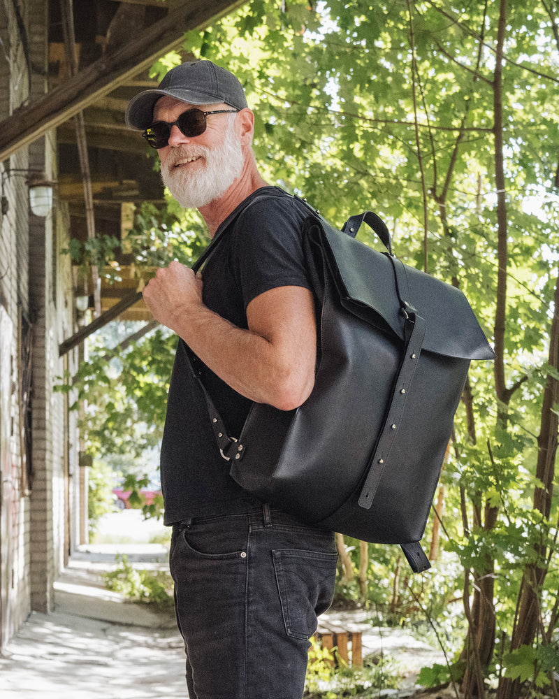 Sac à dos en cuir noir Stella Soomlais, porté sur l'épaule sous les arbres