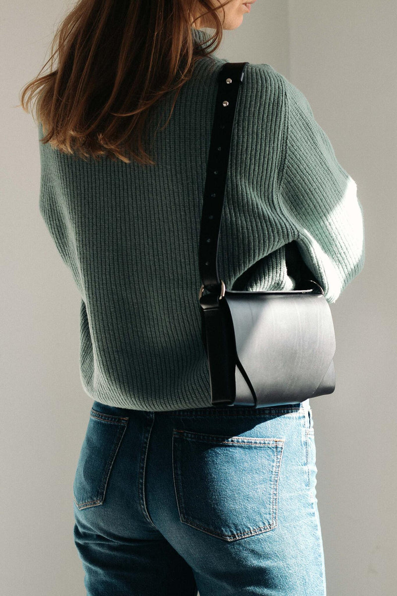Sac bandoulière en cuir noir Stella Soomlais porté à l'épaule, vue de dos