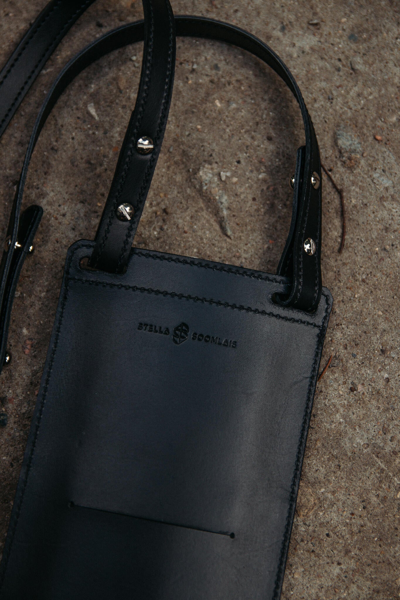 Gros plan sur le dos de la pochette téléphone en cuir noir Stella Soomlais, coutures et rivets des lanières