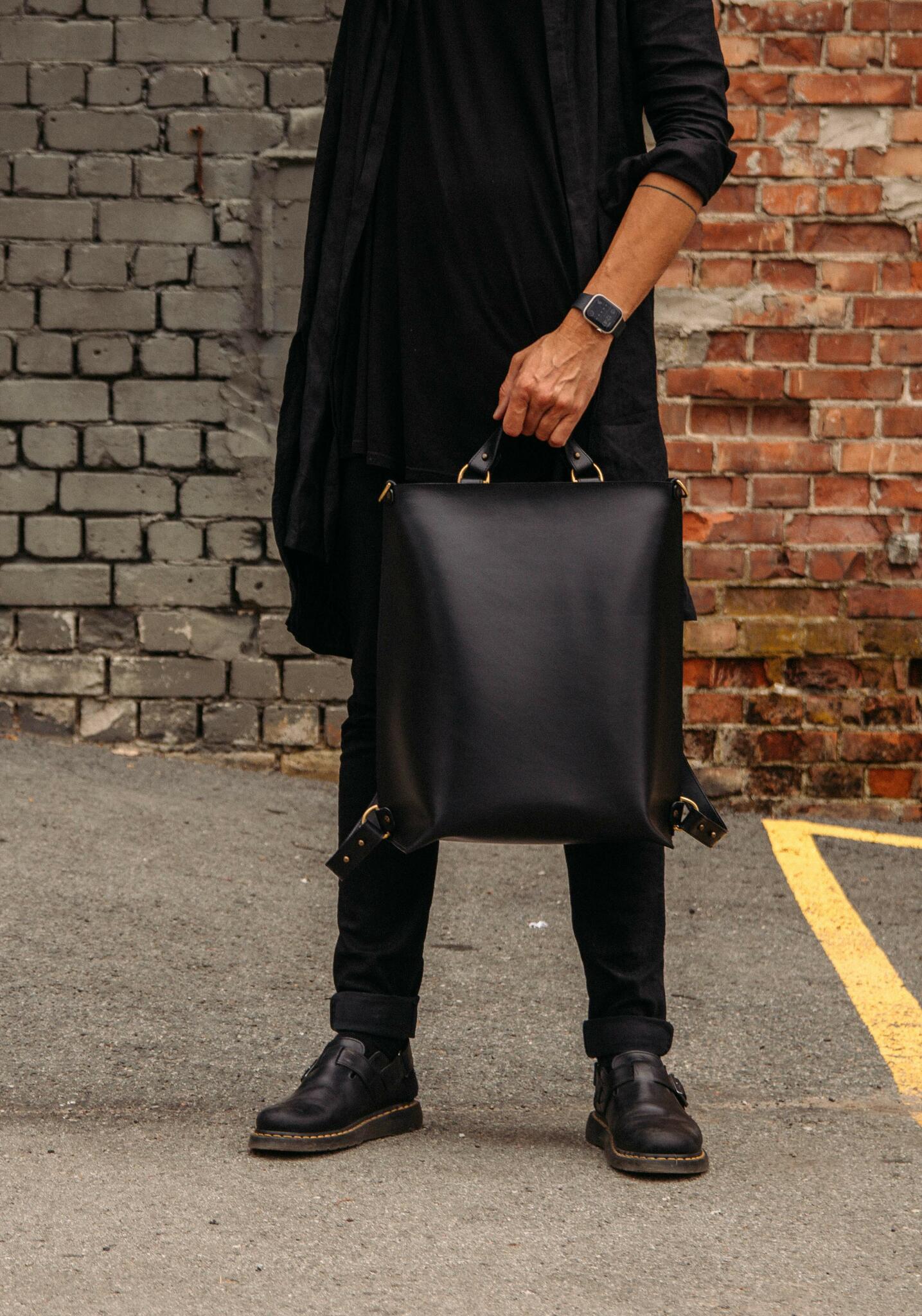 Sac à dos en cuir noir Stella Soomlais tenu par la poignée, boucles laiton visibles