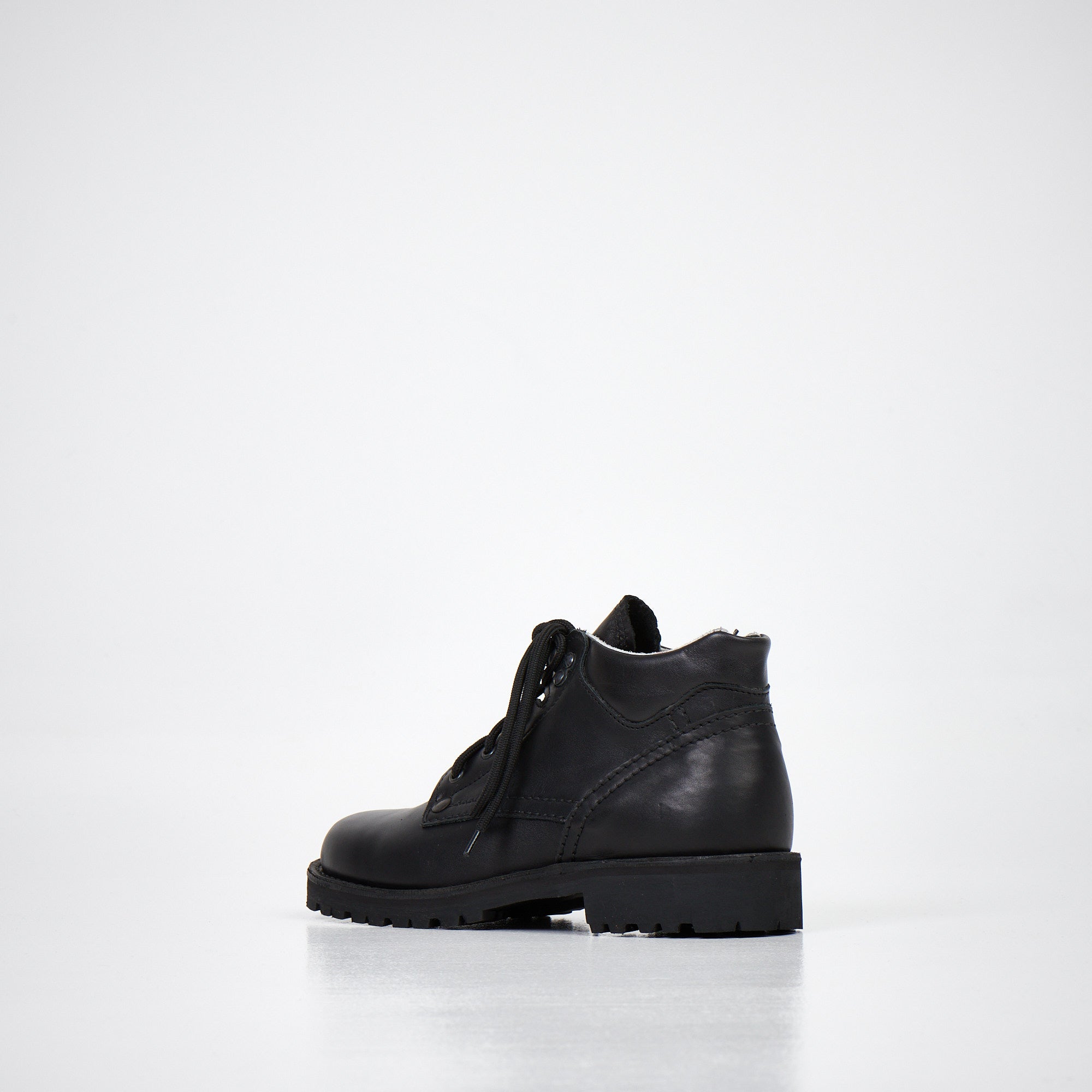 Bottines en cuir noir verni fait main, vue trois quarts sur fond studio blanc