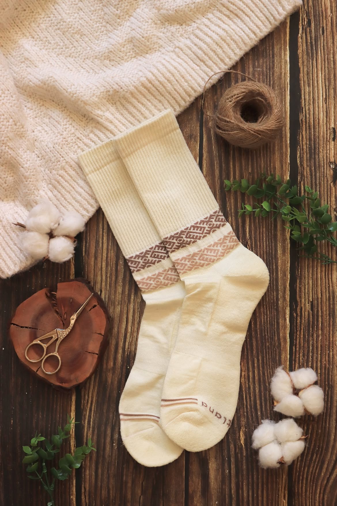Paire de chaussettes en laine mérinos blanches à motifs beige présentée sur une table en bois, Baltland