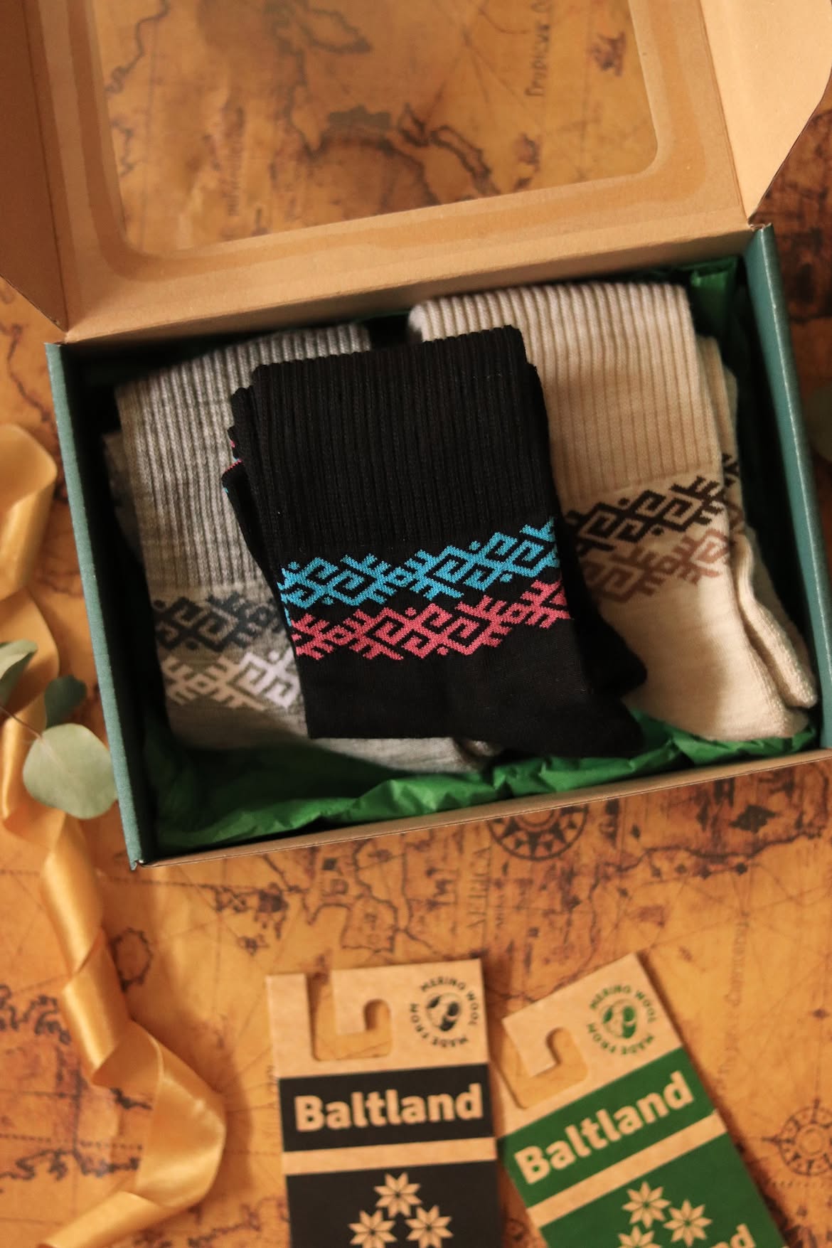 Chaussettes de sport en laine mérinos foncées à motifs orange et verts portées avec un jean, Baltland
