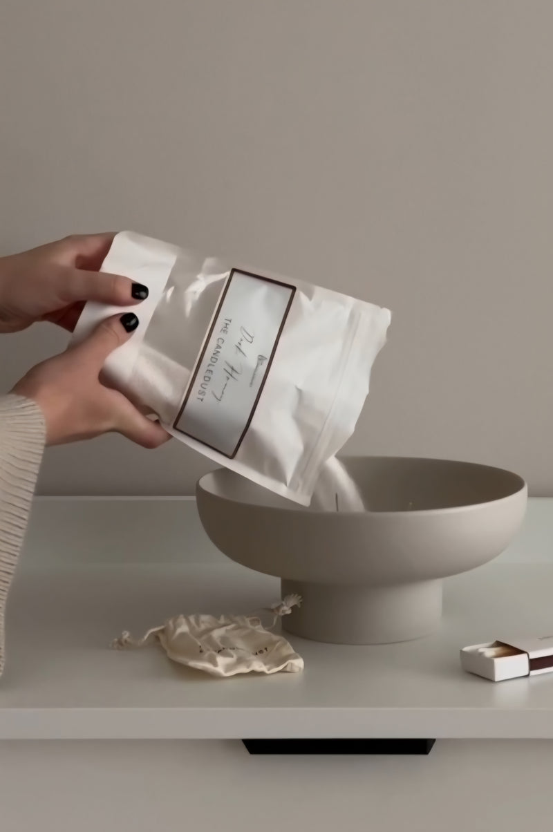 Versement de poudre Candledust dans un bol beige avec sachet et mèche