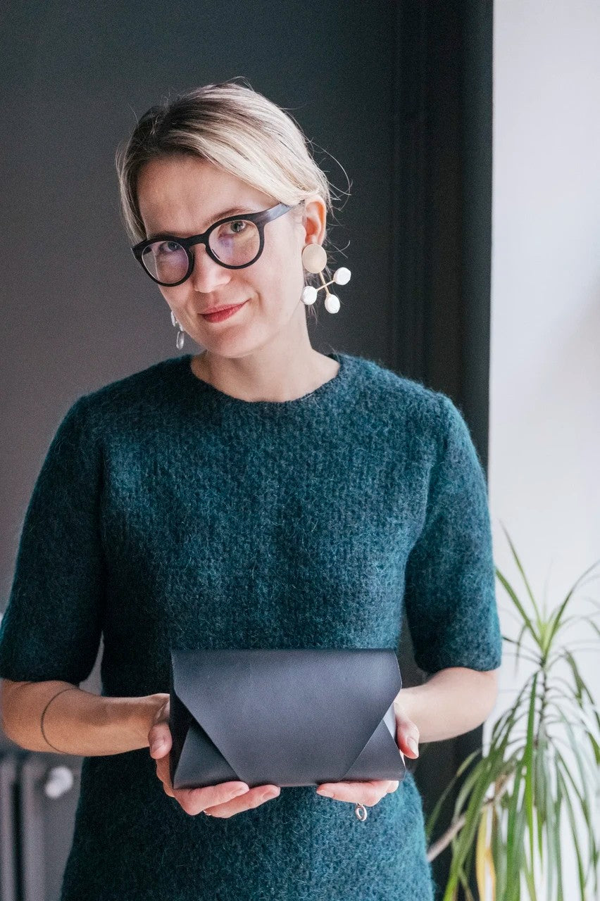 Pochette bandoulière en cuir noir Stella Soomlais tenue fermée à deux mains, vue de face