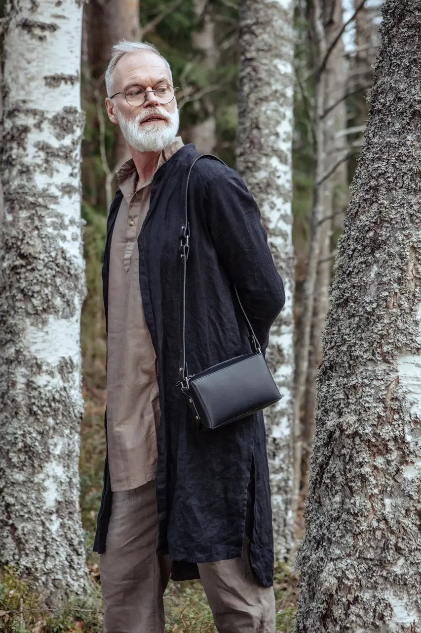 Sac bandoulière en cuir noir Stella Soomlais, porté en travers du corps en forêt