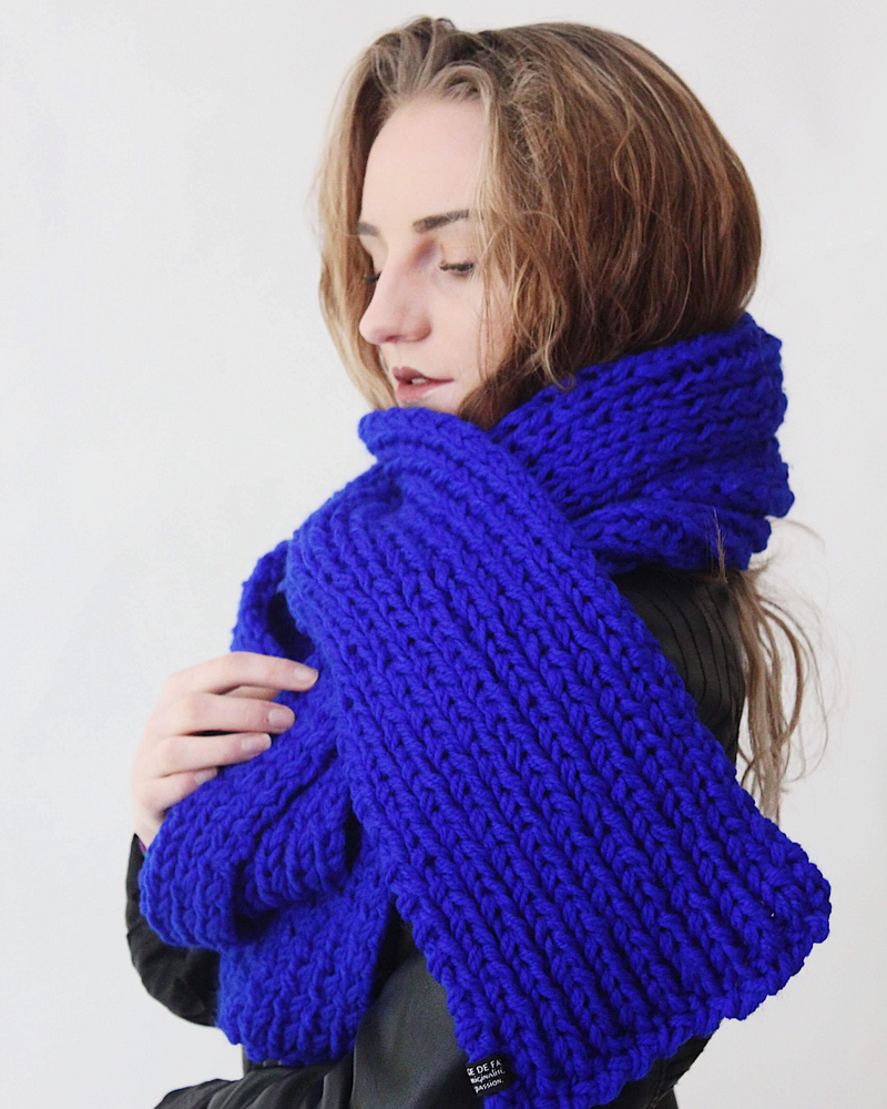 Écharpe en laine bleu électrique tricotée main, pliée sur fond clair pour mettre en valeur la couleur