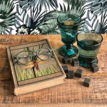 Verres à pied abeille colorés La Rochère vert émeraude, mise en scène avec livre ancien et carrés de chocolat sur table en bois