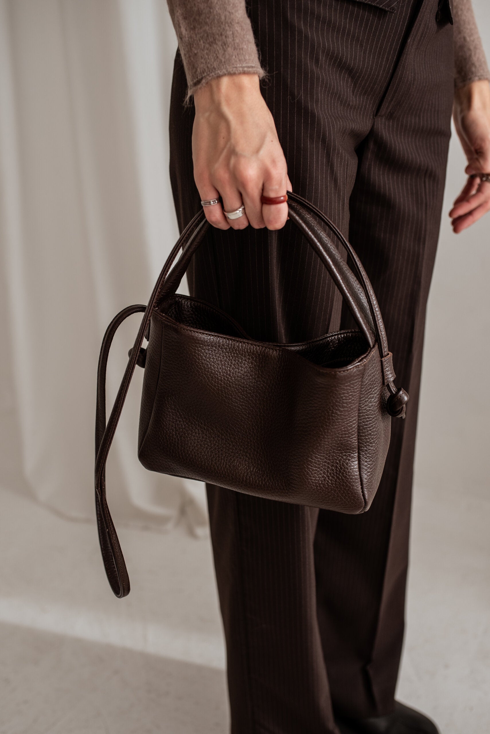Sac crossbody en cuir marron foncé posé à plat, photo studio