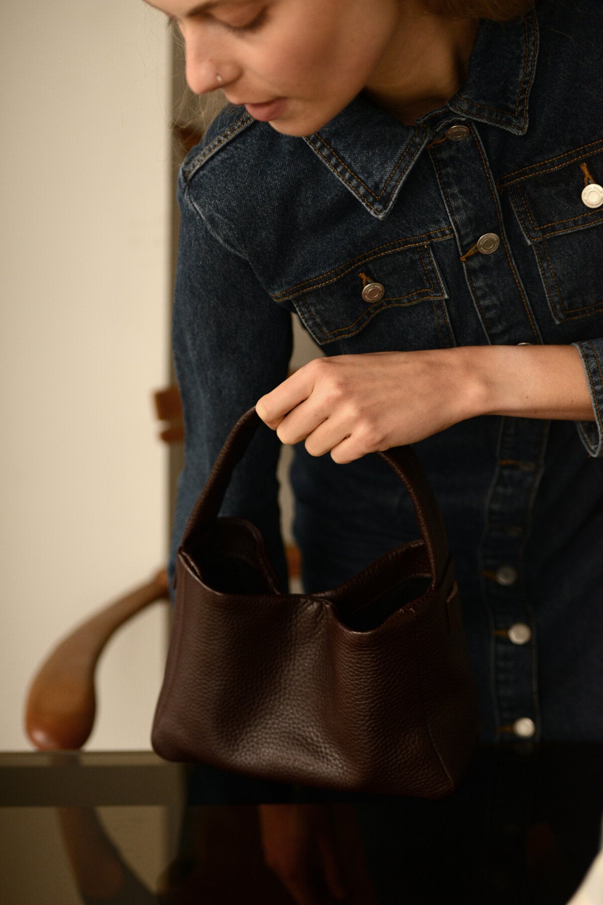 Sac crossbody en cuir marron foncé porté en bandoulière, photo studio mode