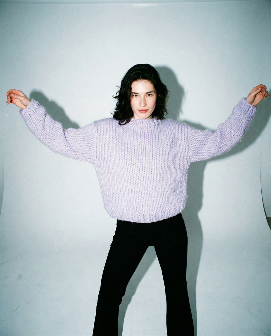Pull en grosse maille de laine lilas tricoté main LeGarage Knitwear, bras écartés pose décontractée