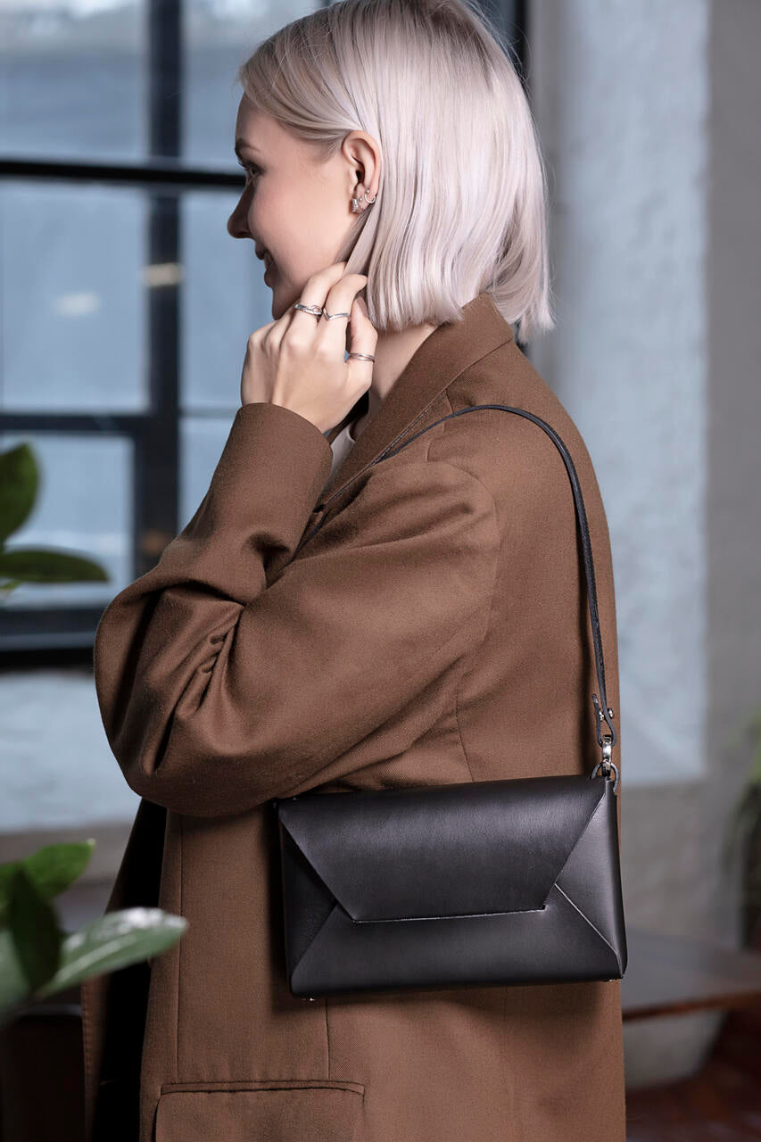 Sac à main en cuir noir Stella Soomlais porté à l'épaule avec fine bandoulière en cuir