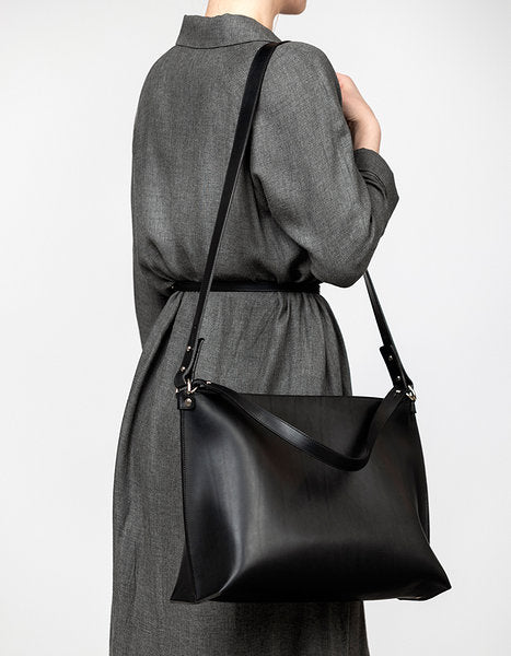 Sac à main en cuir noir Nothing to Declare Stella Soomlais, porté à l'épaule sur une robe grise