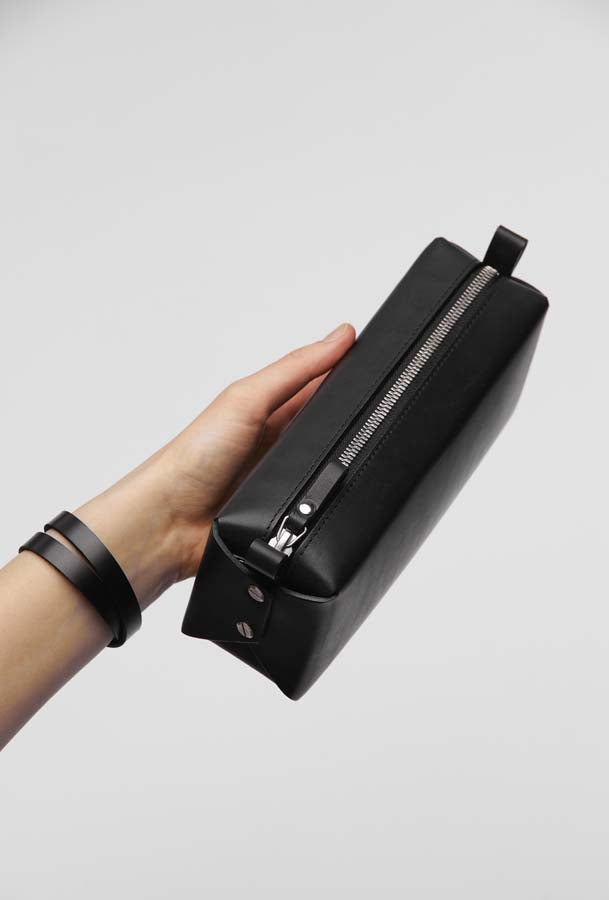 Trousse de maquillage en cuir noir Double-Decker Stella Soomlais, tenue en main de profil