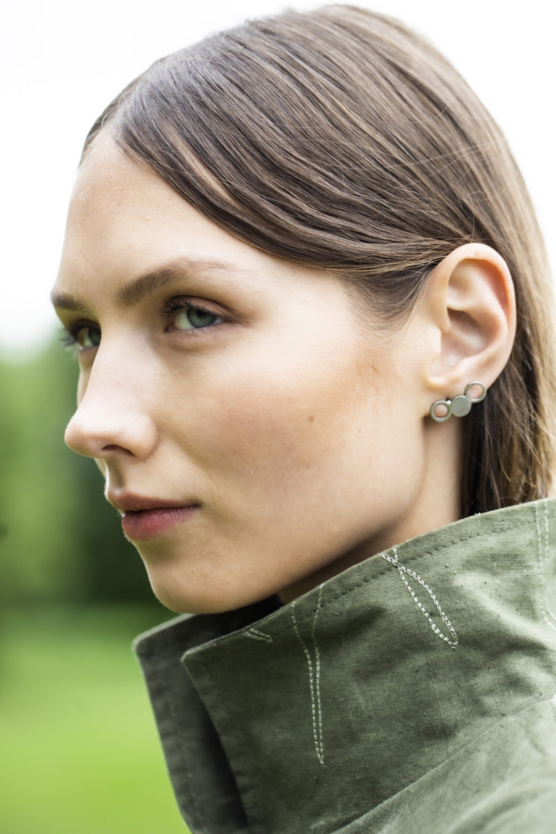 Boucles d'oreilles Lentsius modèle Silva en acier inoxydable portées avec manteau, vue éditoriale