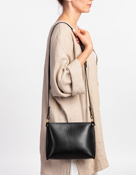 Sac à main en cuir noir Stella Soomlais porté croisé à la hanche, vue de profil