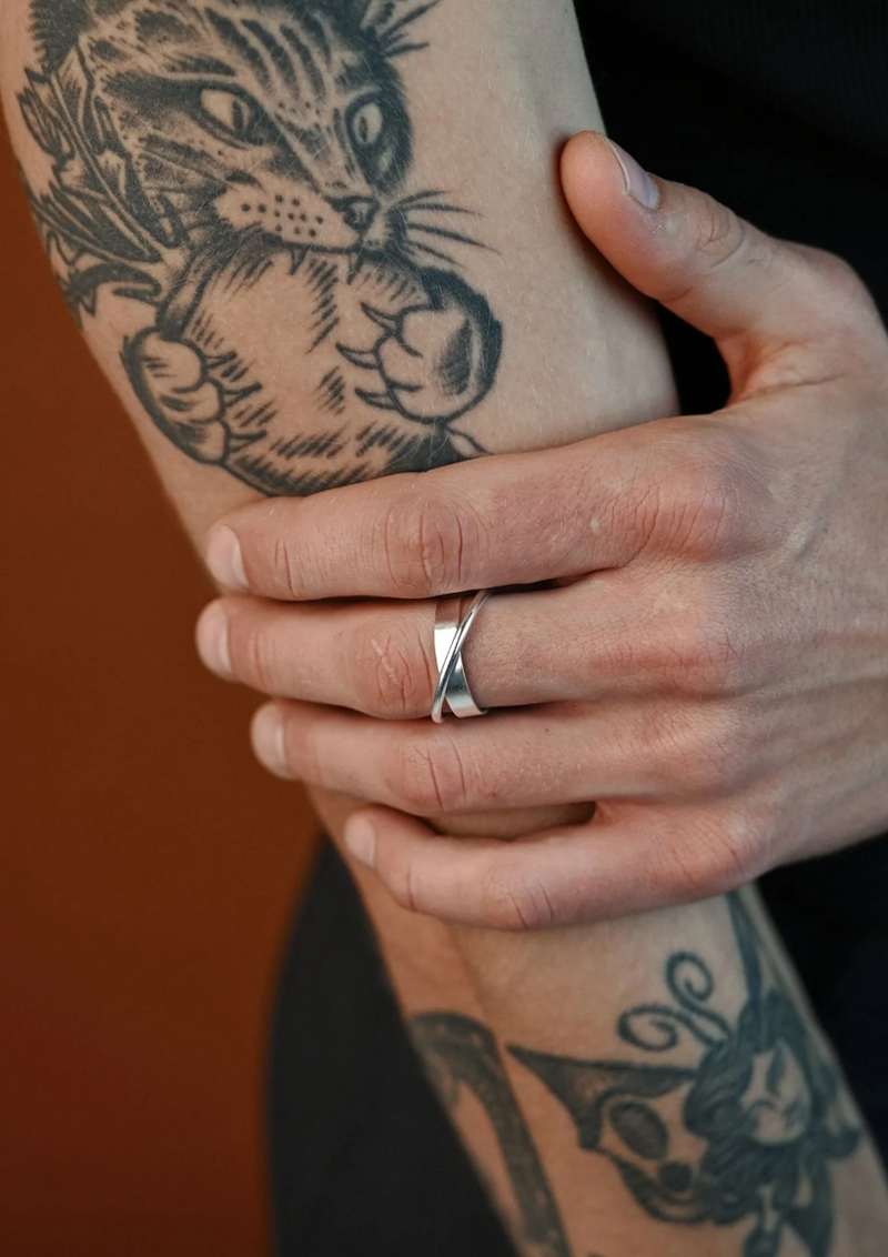 Bague Andromeda NO MORE en argent sterling portée sur un bras tatoué motif chat