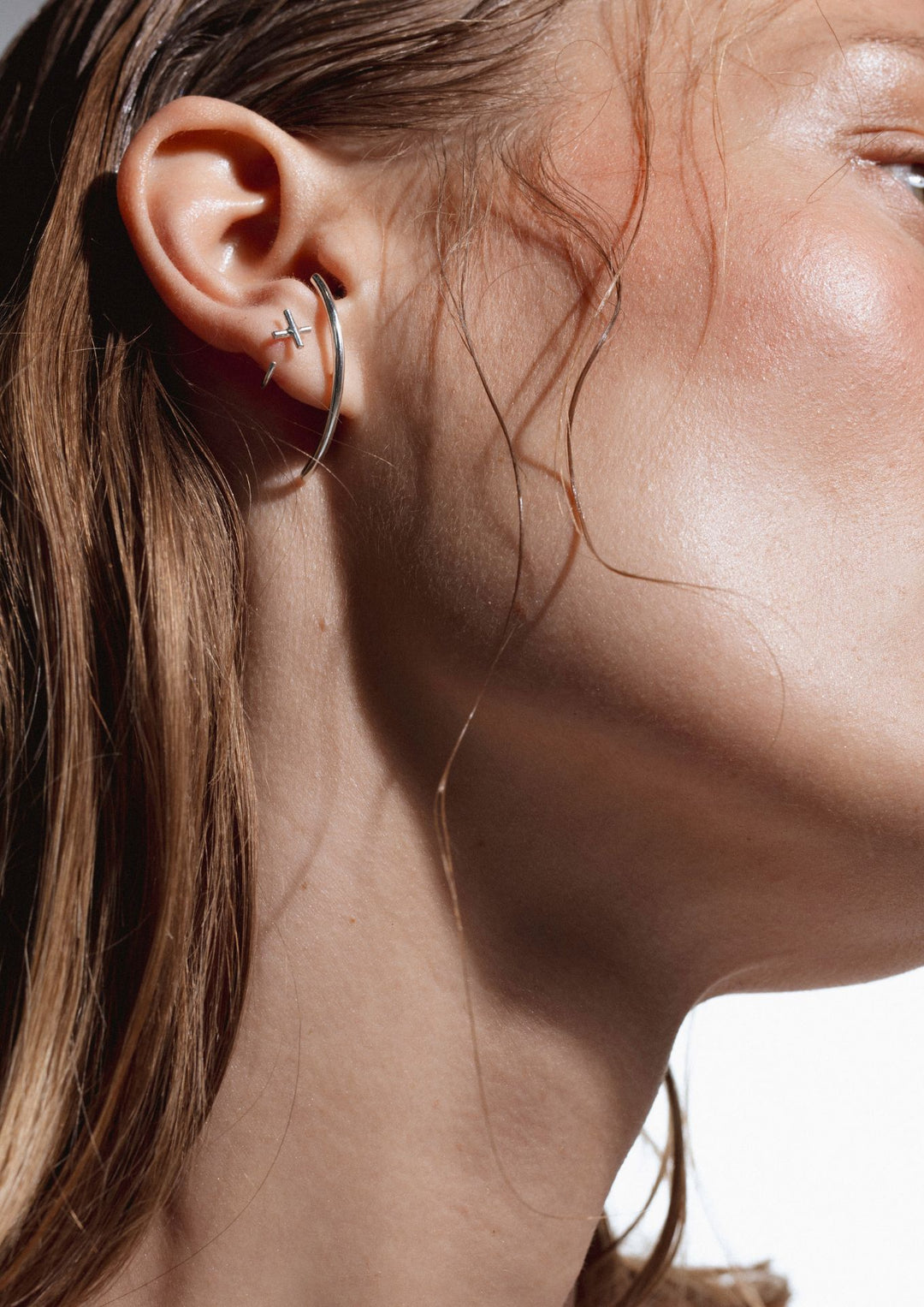Boucles d'oreilles NO MORE en argent portées par femme cheveux longs, vue d'oreille