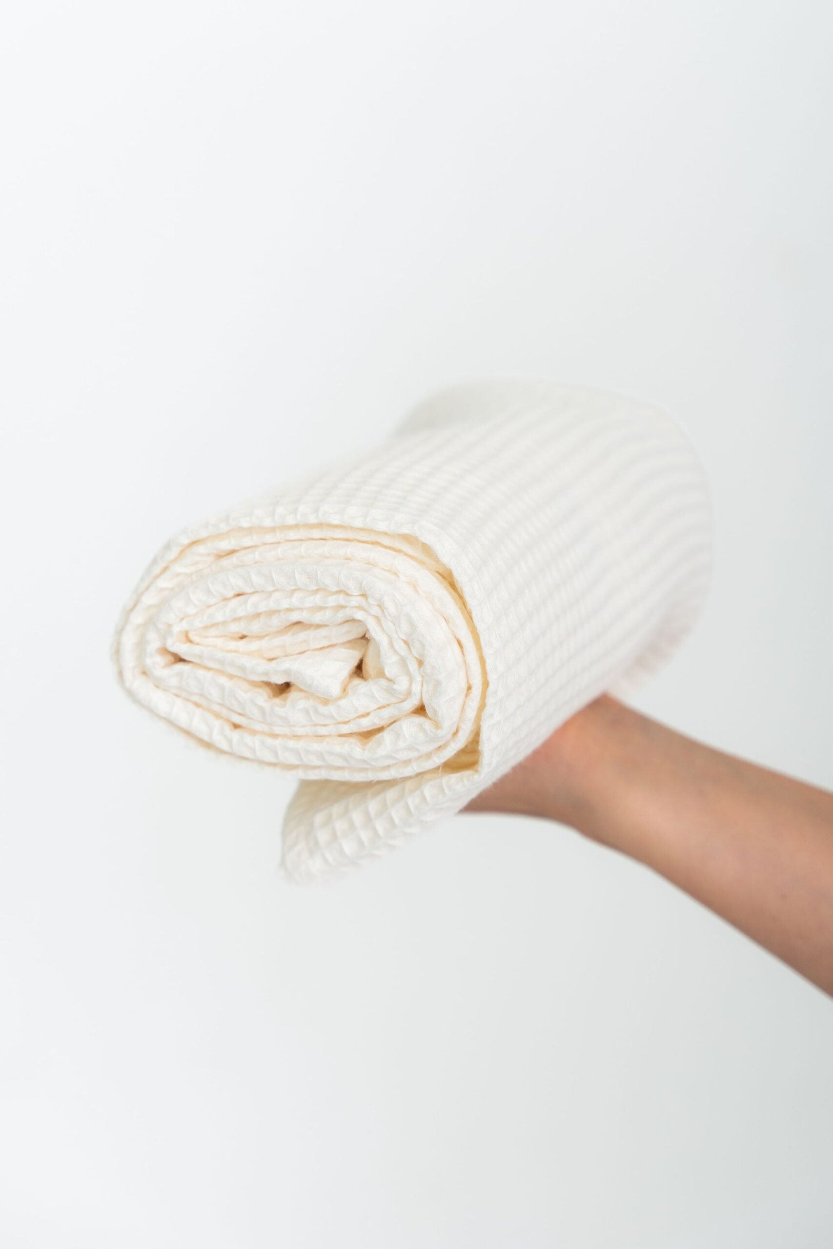 Serviette de bain NUSS en coton bio gaufré crème, drapée pour le séchage