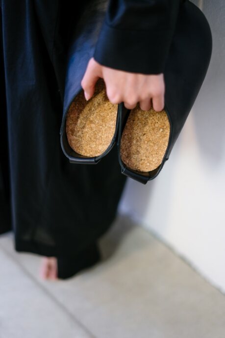 Chaussons Kyoto en cuir noir avec semelle en liège, portés dans une main